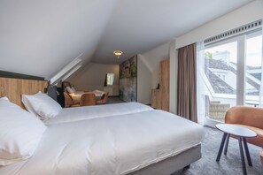 Habitación de hotel con una cama grande, un escritorio y vistas a la ciudad desde la ventana.