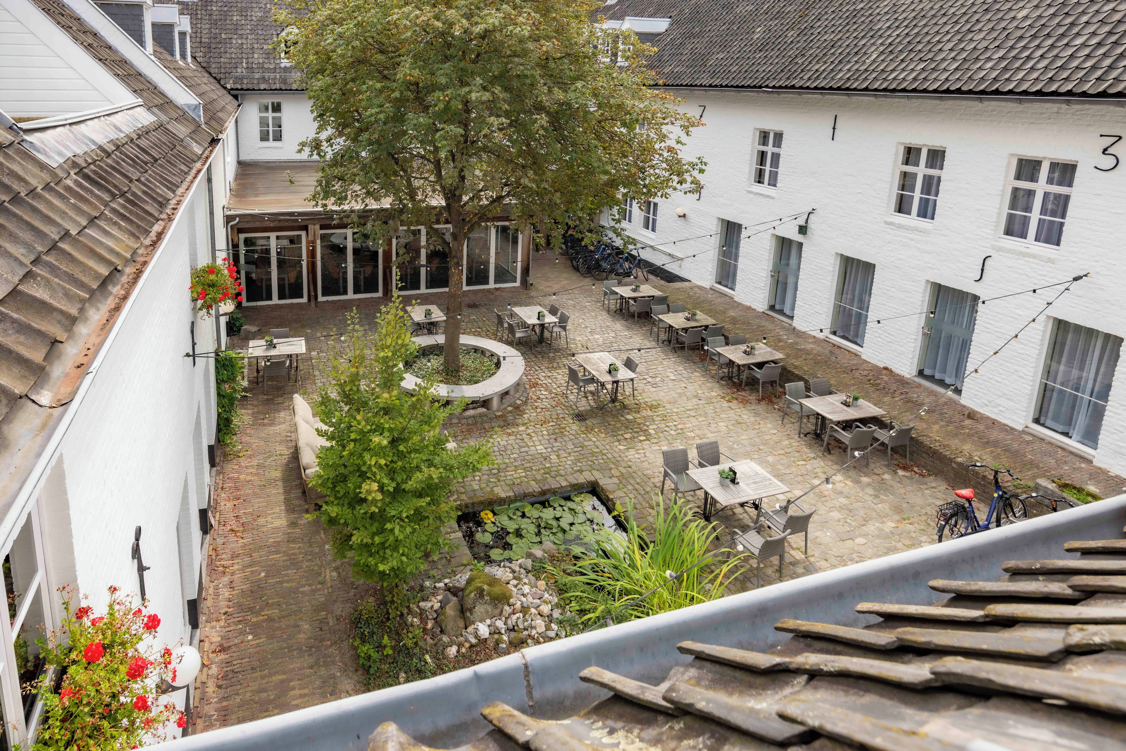Une cour avec des sièges extérieurs, un arbre et un petit étang.