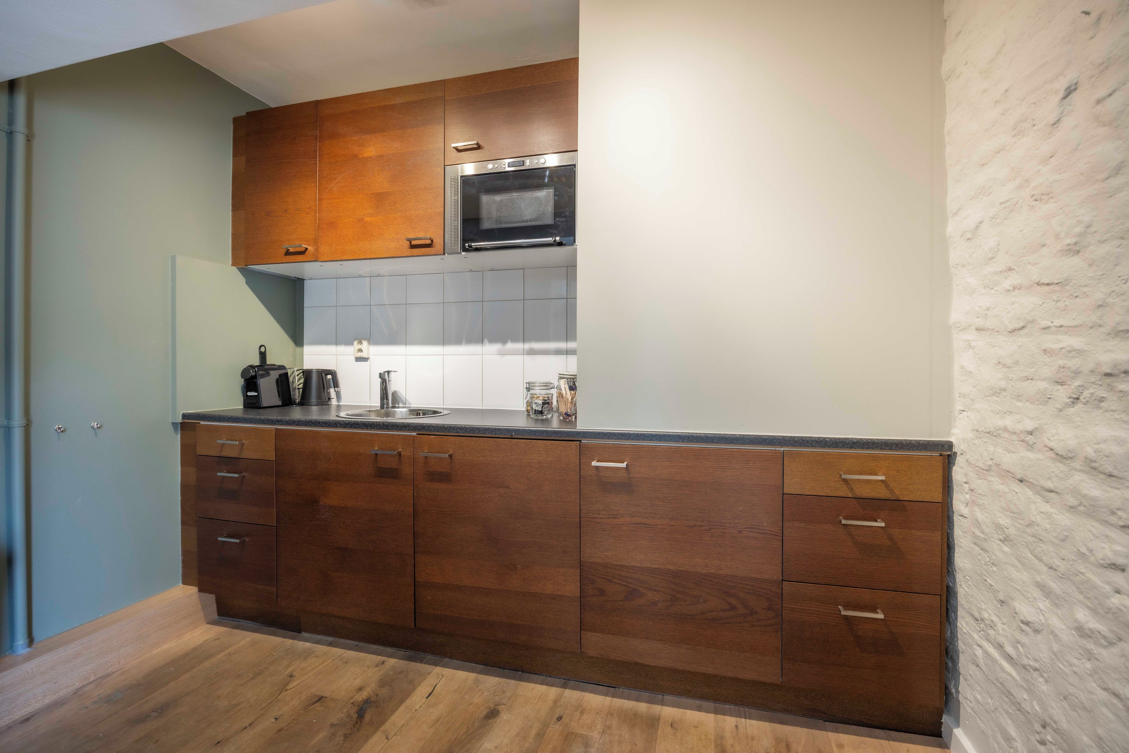 Una cocina moderna con armarios de madera, un microondas de acero inoxidable y una encimera de granito.