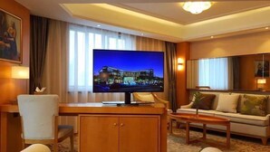 A hotel room with a large flat-screen TV, a wooden desk, a sofa, and a bed. - Jinling Mingdu Hotel Changzhou (Changzhou)