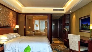 A hotel room with a large bed, a desk with a chair, a large window with blinds, and a decorative wall. - Jinling Mingdu Hotel Changzhou (Changzhou)