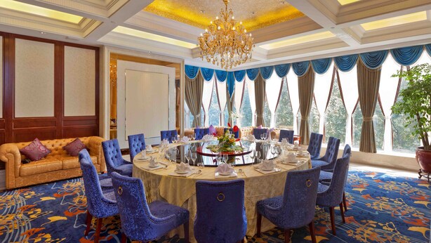 A formal dining room with a round table set for six, surrounded by blue upholstered chairs. - Jinling Mingdu Hotel Changzhou (Changzhou)