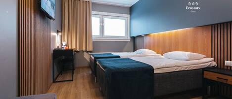 A modern hotel room with a large bed, a desk, and a TV mounted on the wall.