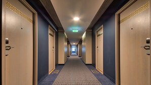 A hotel hallway with carpeted floors, numbered doors, and a visible exit sign. - Go Hotel Shnelli (Tallinn)