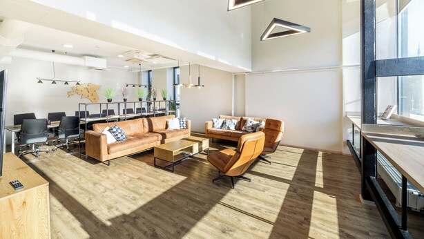 A modern office space with a large meeting table, leather sofas, and a wooden coffee table. - Go Hotel Shnelli (Tallinn)