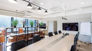 A modern conference room with a long table, black chairs, and a whiteboard. - Go Hotel Shnelli (Tallinn)