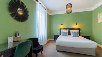 A bedroom with a bed, a desk, a chair, and a wall-mounted light fixture.