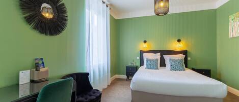 A bedroom with a bed, a desk, a chair, and a wall-mounted light fixture.