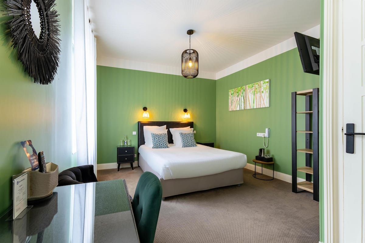 A neatly arranged bedroom with a bed, bedside tables, a desk, and a chair.