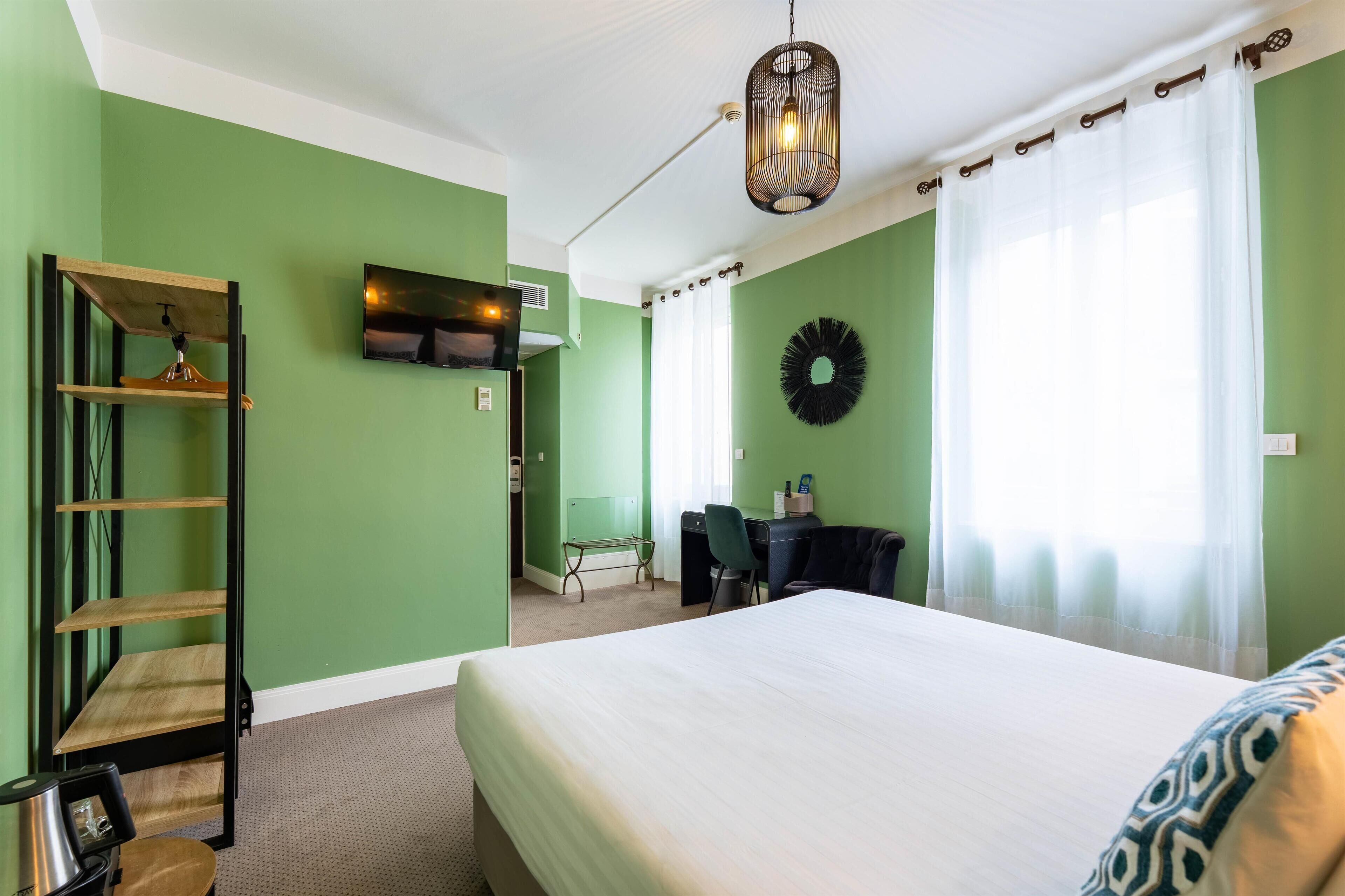 Une chambre d’hôtel équipée d’un lit, d’un bureau, d’une chaise, d’une télévision et d’une étagère.