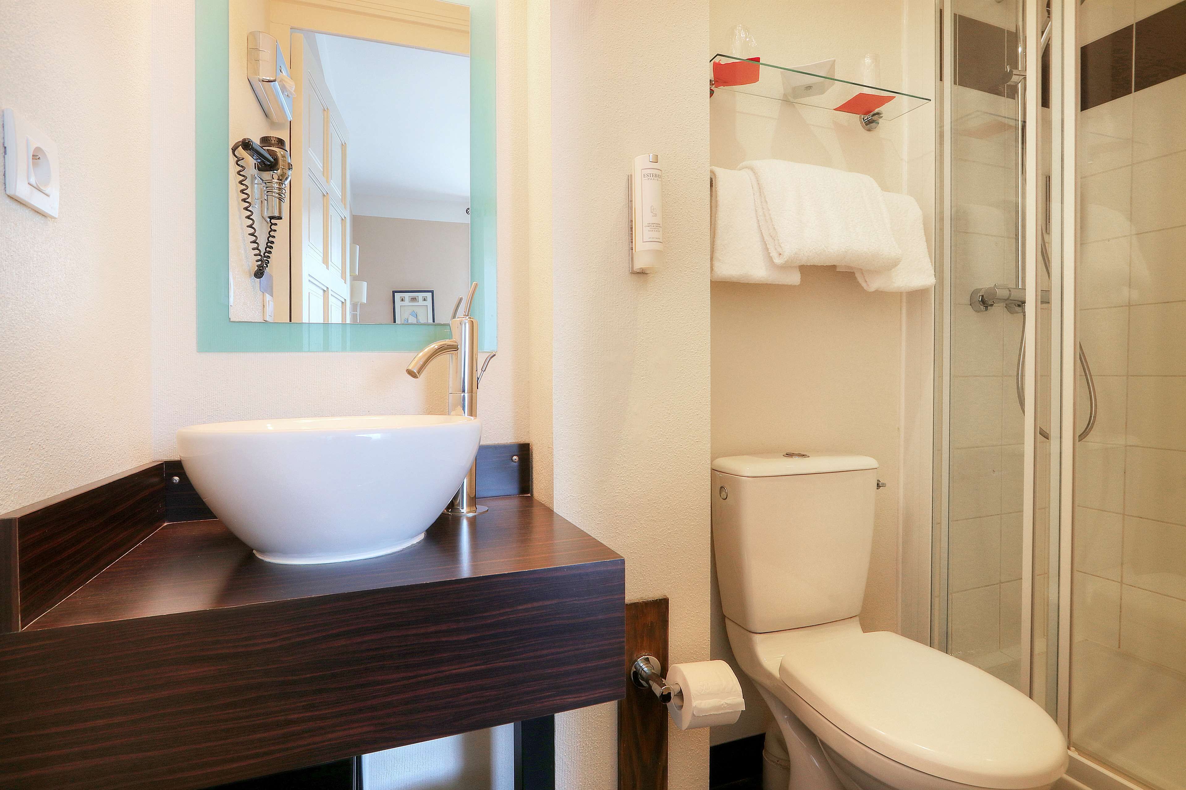 A bathroom with a white sink, a toilet, and a glass shower enclosure.