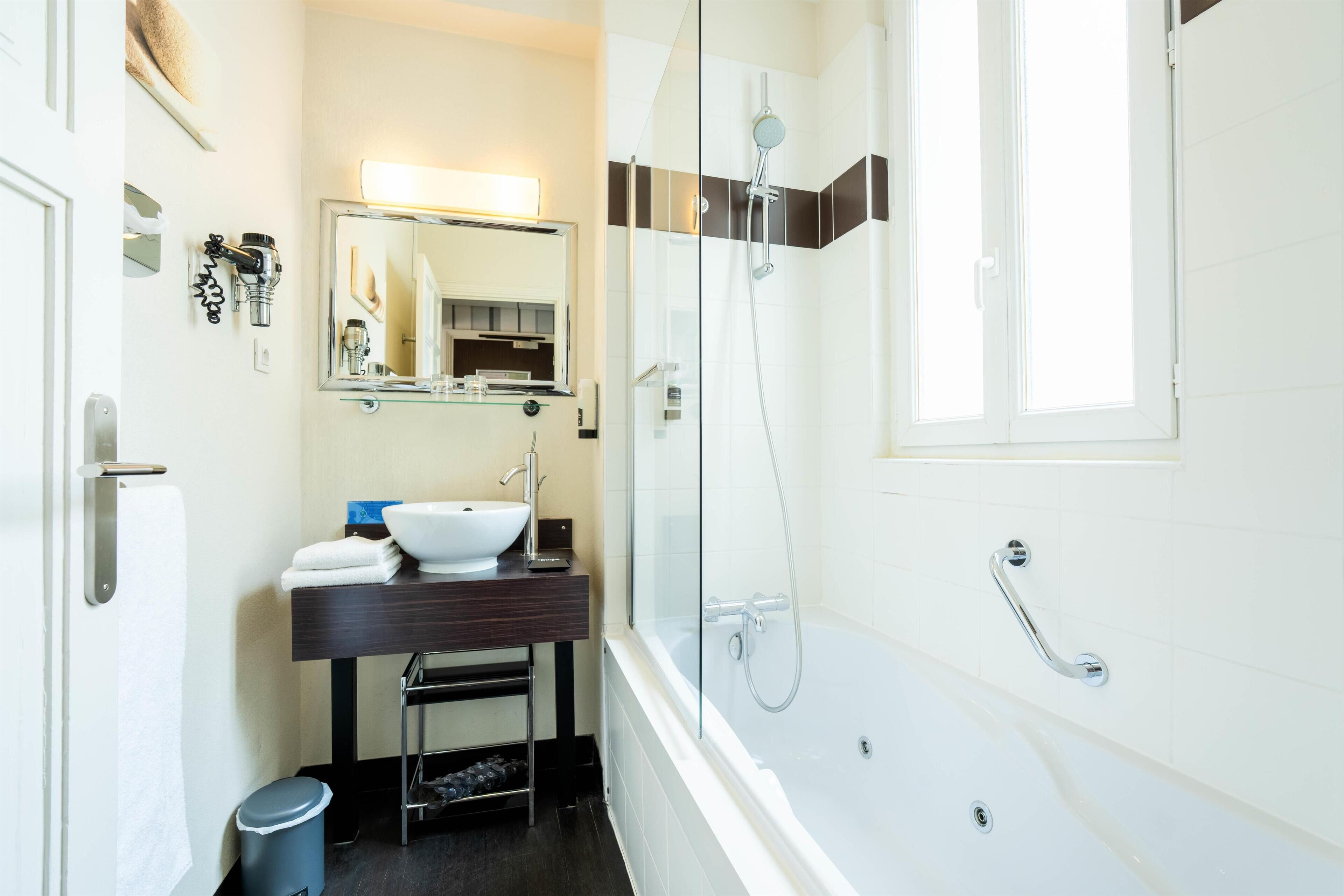 A modern bathroom with a glass-enclosed shower, a white sink, and a mirror above the vanity.