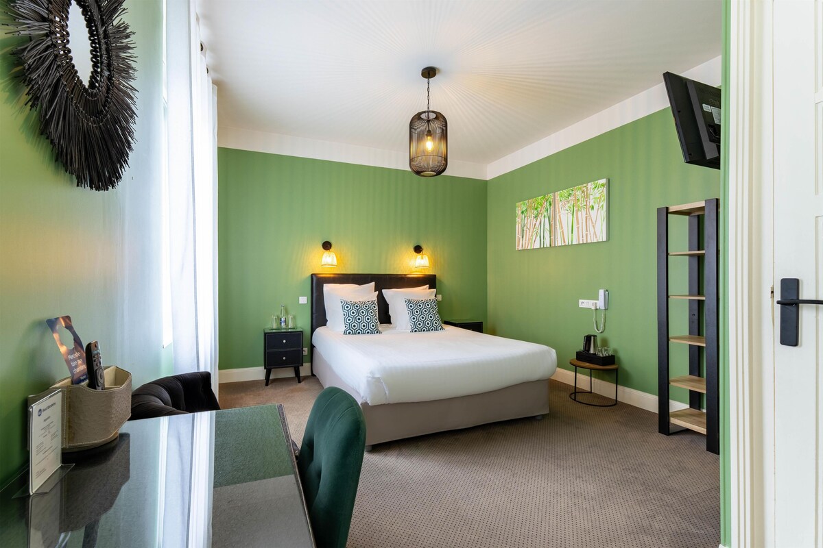 A neatly arranged bedroom with a bed, bedside tables, a desk, and a chair.