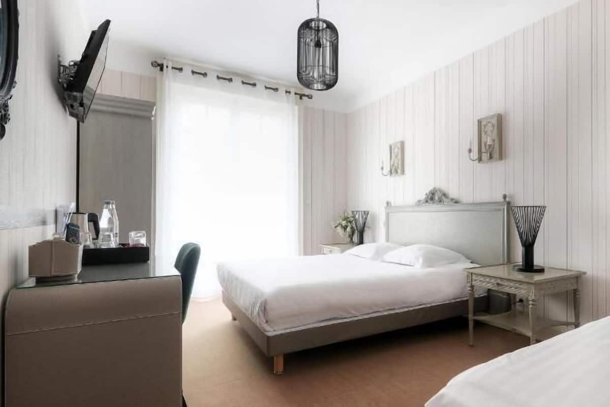 A bedroom with a bed, bedside table, lamp, and a chair.