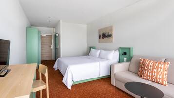 Ein modernes Hotelzimmer mit einem Bett, einer Couch, einem kleinen Tisch und einem Schreibtisch.
