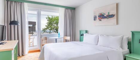 A hotel room with a bed, a desk, a chair, and a window with curtains.
