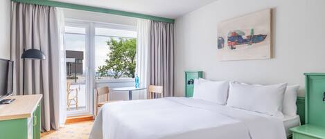 Une chambre d’hôtel équipée d’un lit, d’un bureau, d’une chaise, d’une table et offrant une vue sur l’extérieur.