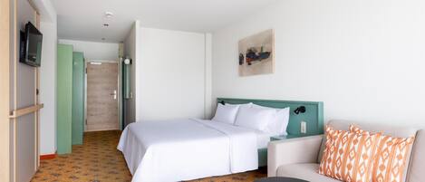 A hotel room with a bed, a sofa, a small table, and a television.