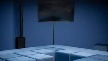 Una habitación moderna con un sofá modular, un televisor de pantalla plana montado en la pared y una lámpara de techo.