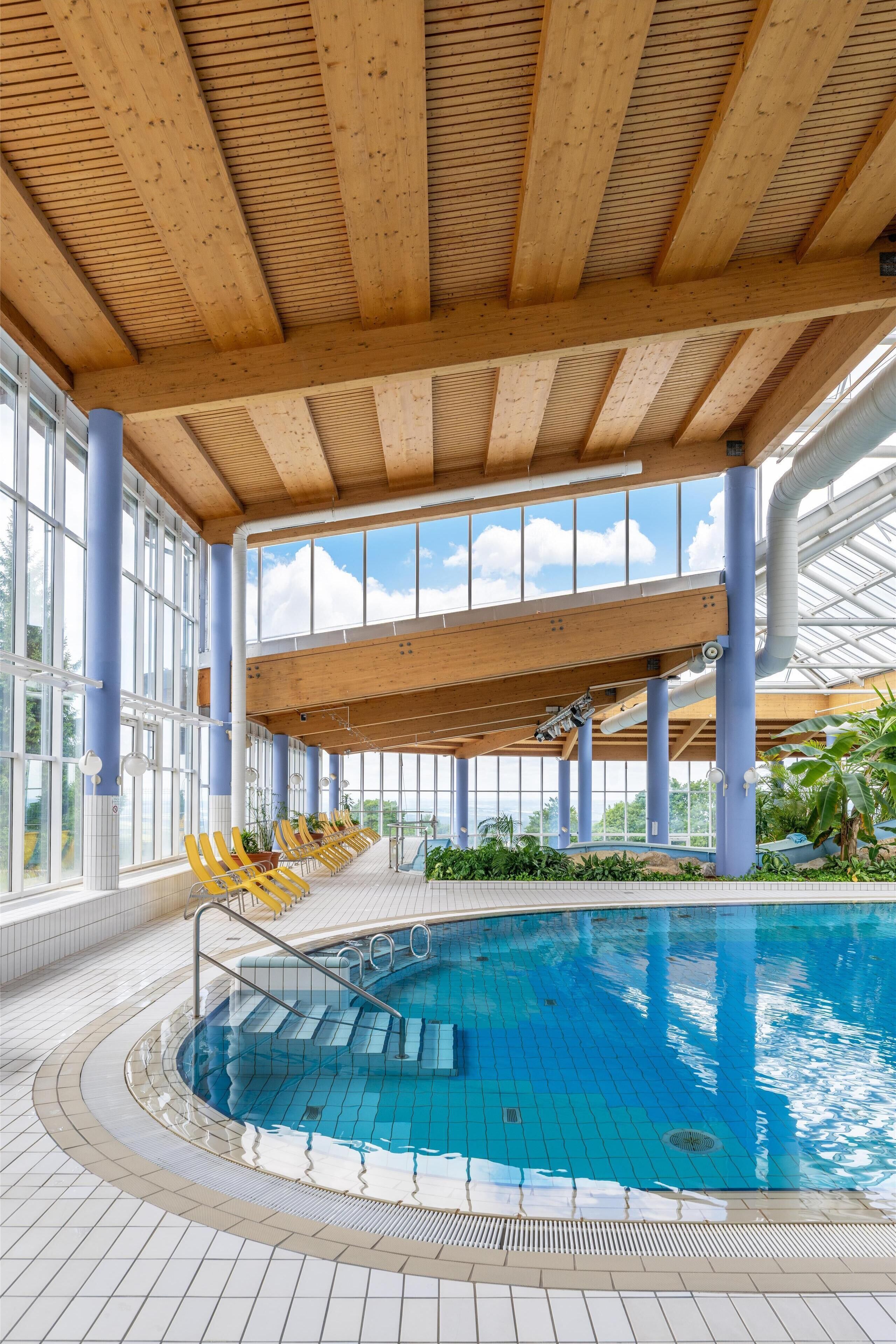 Una piscina interna con travi in legno e ampie finestre.