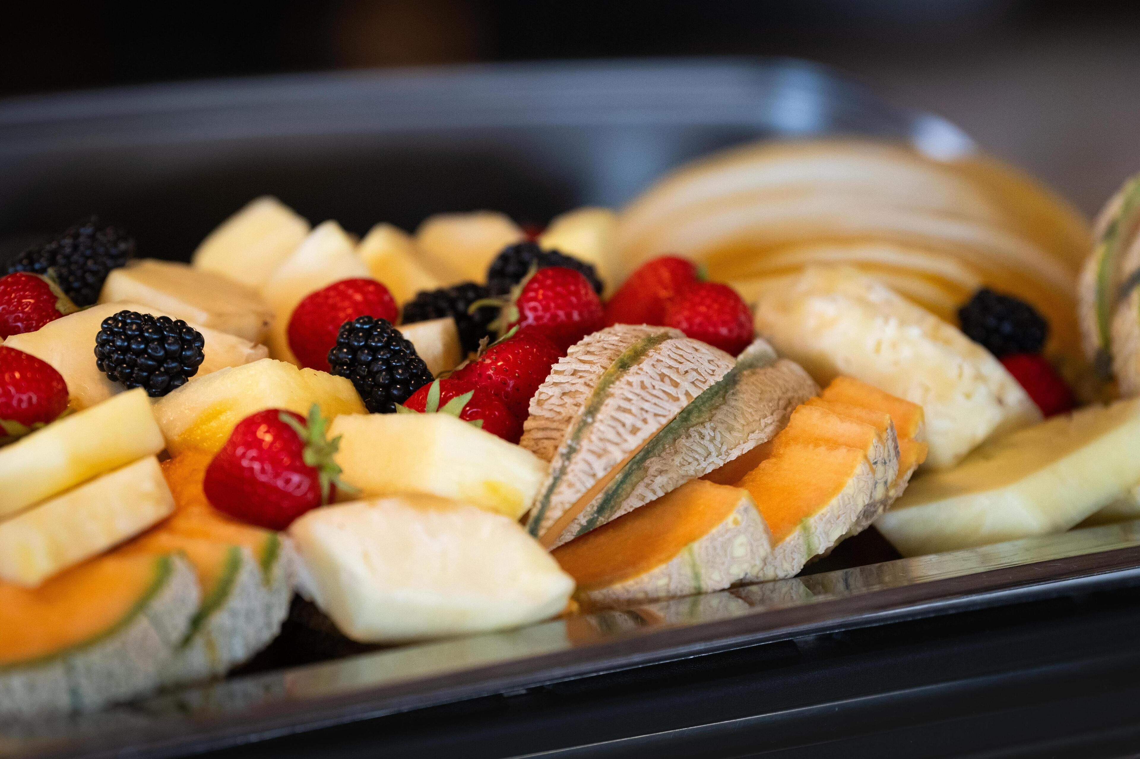 Eine Auswahl an Früchten, darunter Bananen, Erdbeeren, Brombeeren und Cantaloupe-Melone.