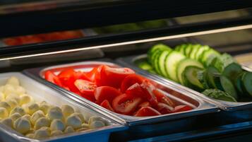 A buffet with various food items including sliced tomatoes, cucumbers, and other vegetables.