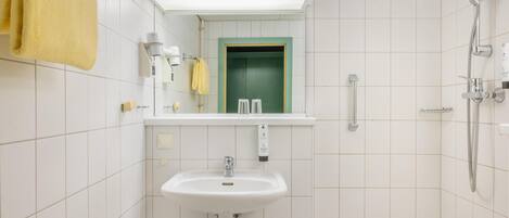 A bathroom with a sink, mirror, towel rack, shower, and toilet.