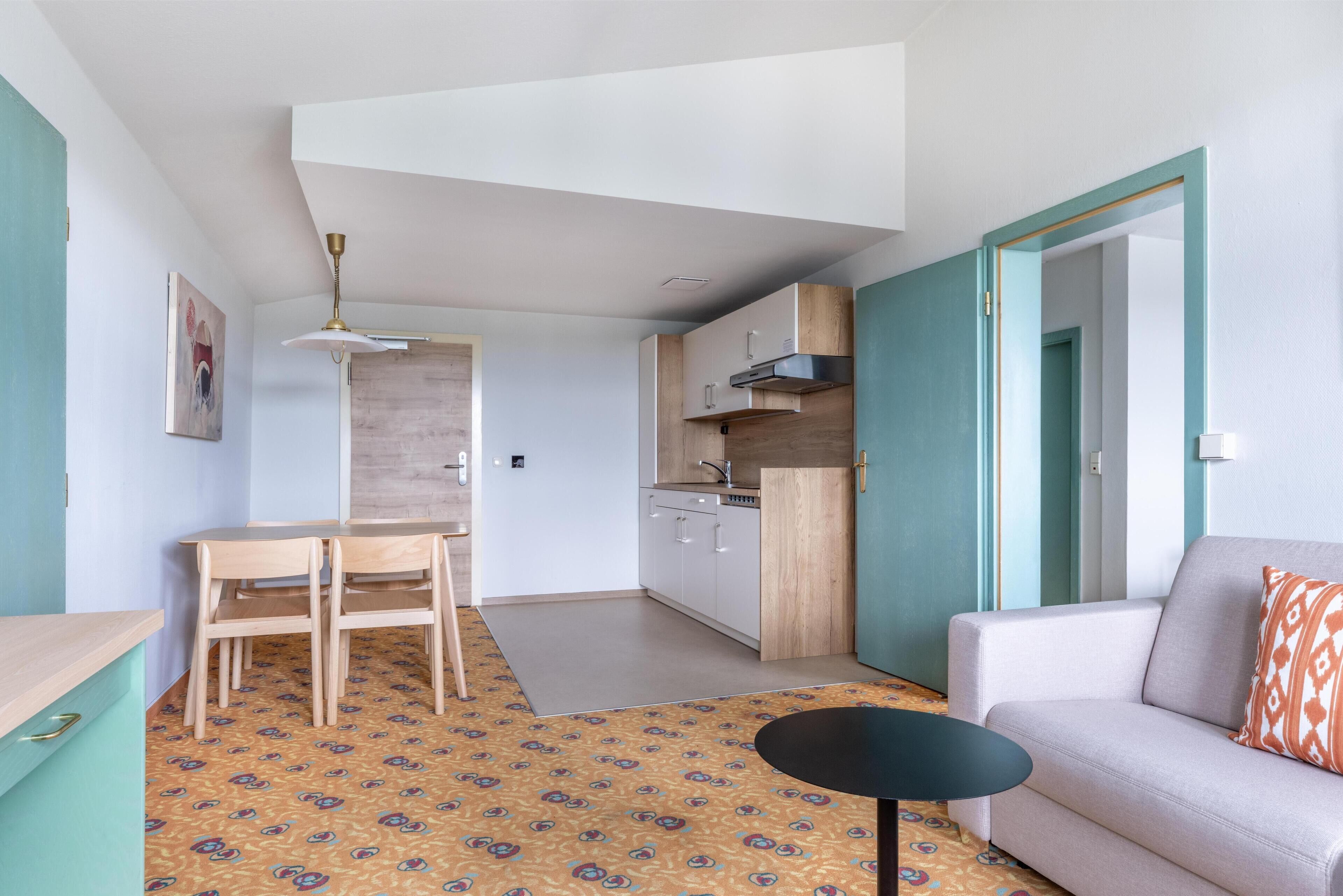 A compact living space with a kitchenette, a dining area, and a sofa.