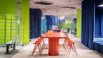A conference room with a long table, orange chairs, and a laptop on the table.
