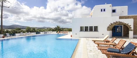 Una piscina al aire libre, sombrillas, tumbonas