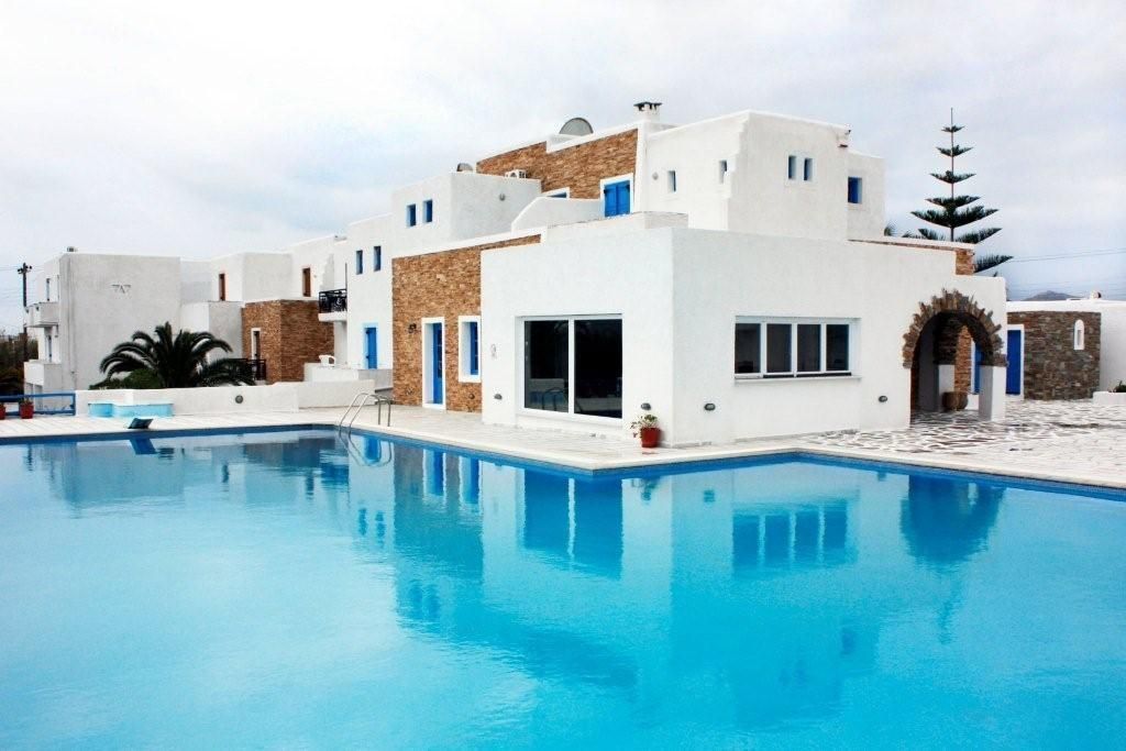 Un edificio moderno con piscina, con elementos arquitectónicos blancos y azules y fachada de piedra.