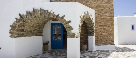 A building with a blue door, stone walls, and a stone-tiled courtyard.