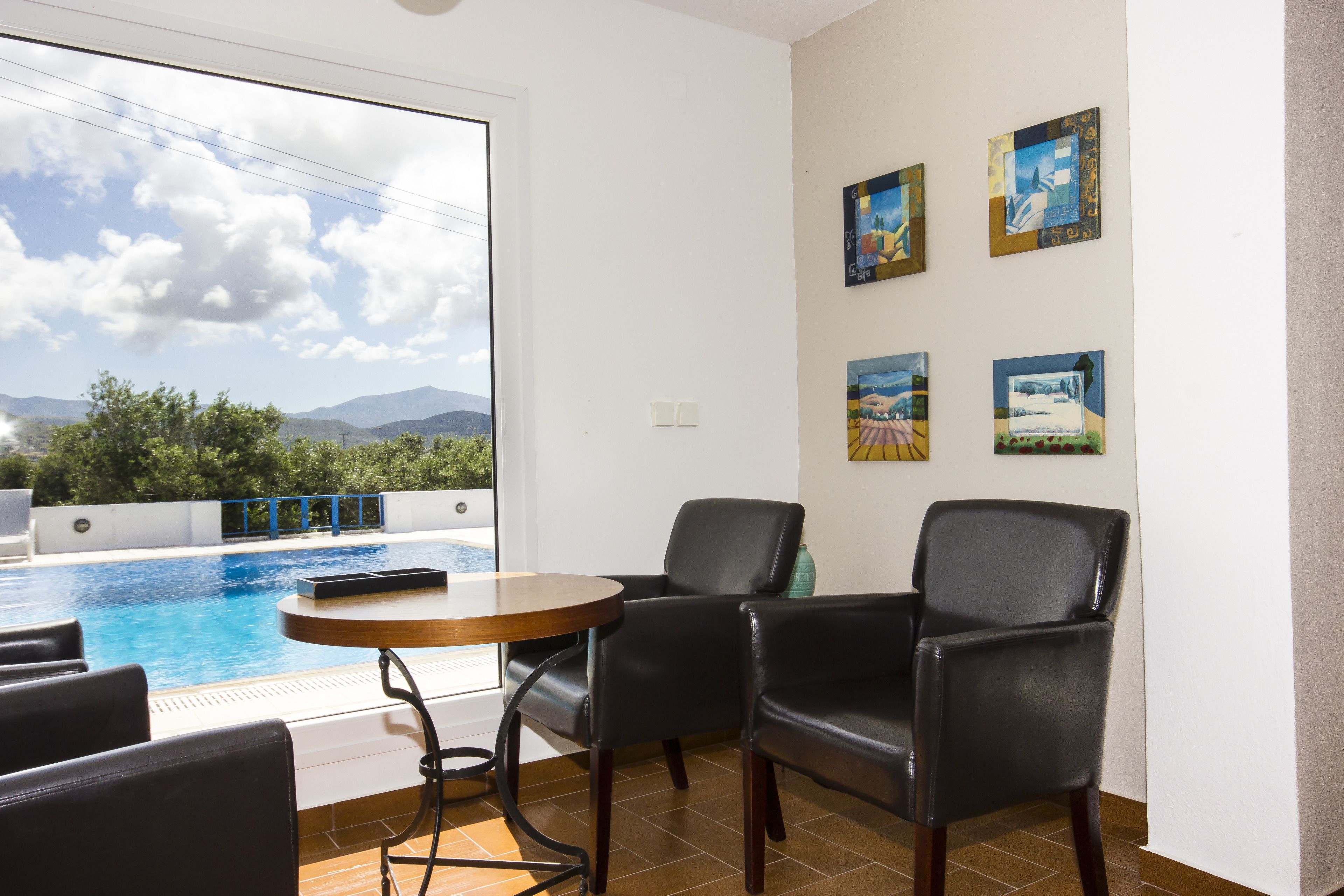 Una habitación con piscina, una mesa y dos sillas. Hay cuadros en la pared.