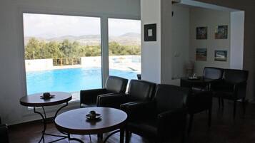 Una sala con vistas a una piscina y montañas. Hay dos mesas redondas y cuatro sillas.