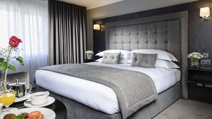 A modern hotel room with a large bed, a bedside table with a lamp, and a breakfast tray. - Killarney Oaks Hotel (Killarney)