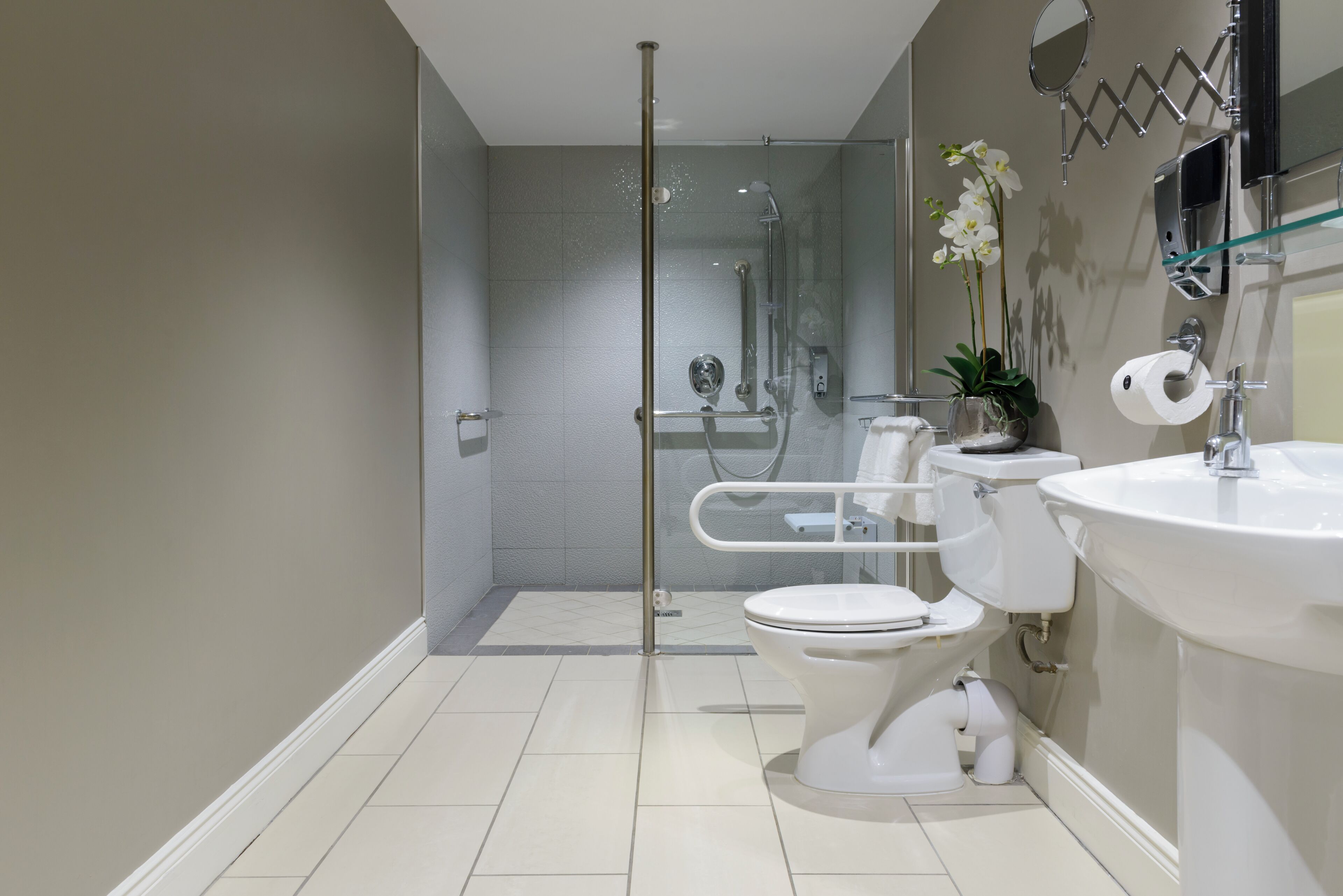 A modern bathroom with a glass-enclosed shower, a toilet, and a sink.