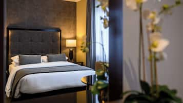 A modern hotel room with a large bed, a nightstand, a lamp, and a vase with flowers.