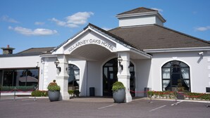 The exterior of the Larney Oaks Hotel with a clear entrance, large potted plants, and a red rope barrier. - Killarney Oaks Hotel (Killarney)