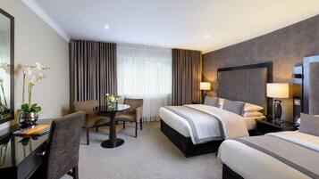 A hotel room with a large bed, a desk with a chair, a small table with a chair, and a large mirror.