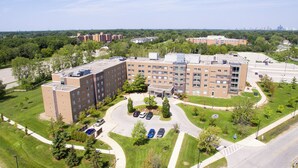 A multi-story building with a parking lot, surrounded by greenery and a clear sky. - Residence & Conference Centre - Windsor (Windsor)