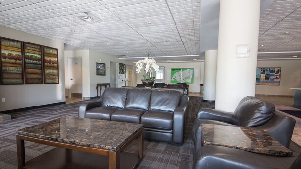A lobby with a leather sofa, a marble coffee table, and a chandelier. - Residence & Conference Centre - Windsor (Windsor)