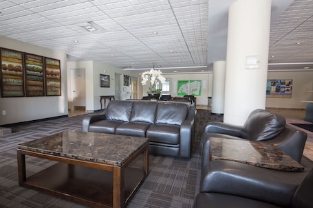 A lobby with a leather sofa, a marble coffee table, and a chandelier.