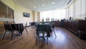 A conference room with a large table, chairs, a television, and a kitchen area with cabinets and appliances. - Residence & Conference Centre - Windsor (Windsor)