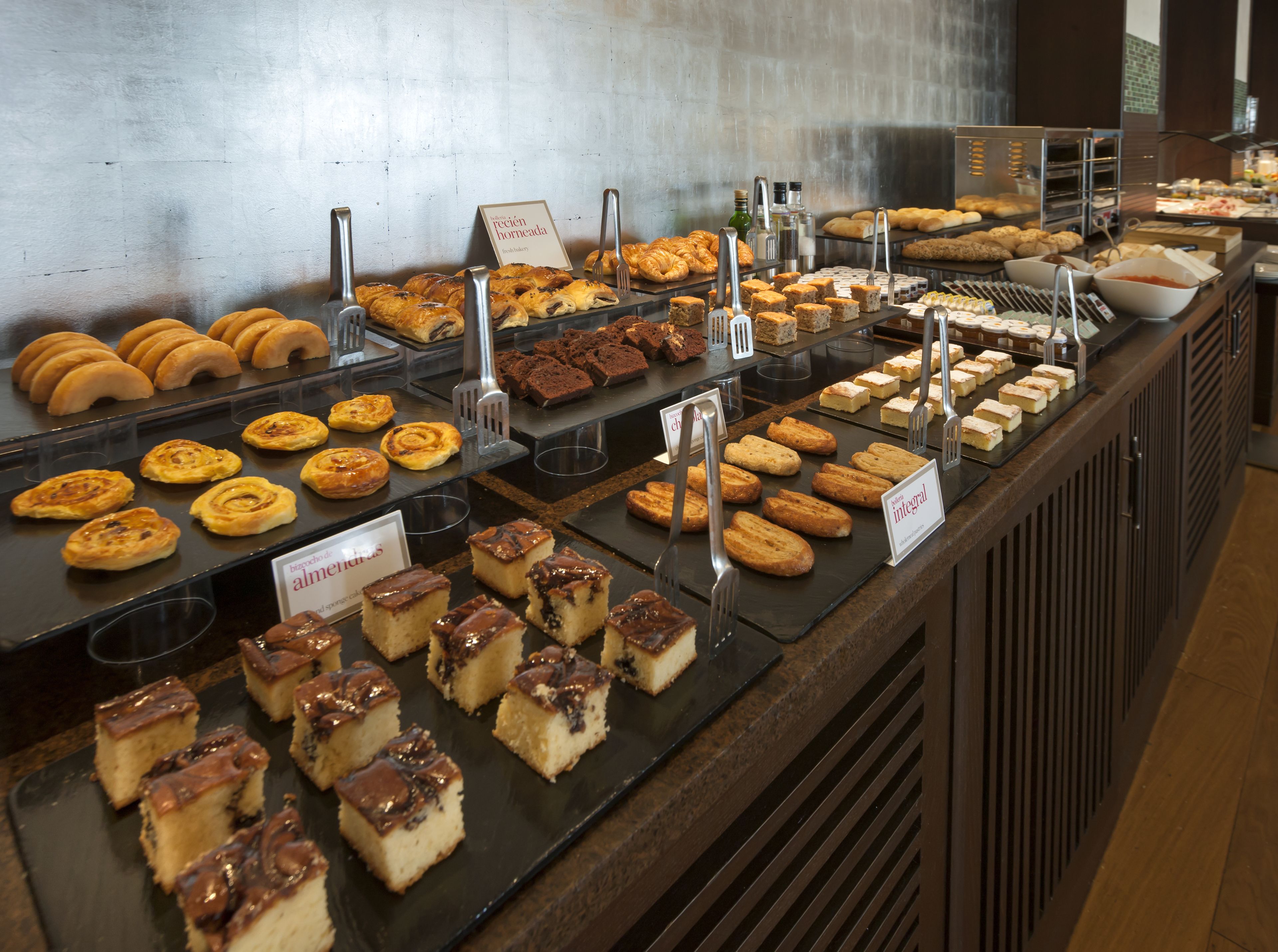 Un bufé con diversos productos de panadería y postres.