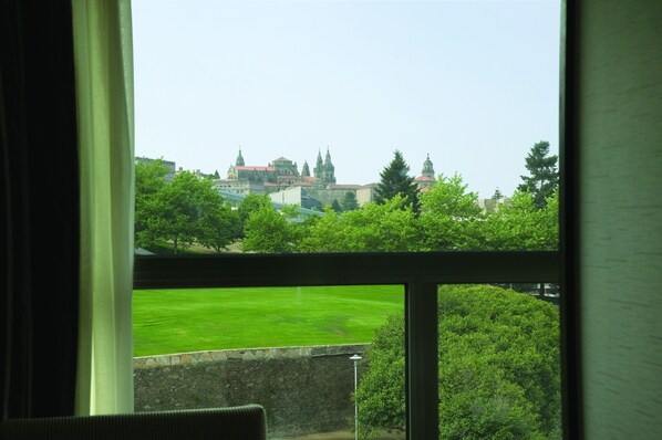 Vista desde una ventana sobre un césped verde y un edificio con varias torres.