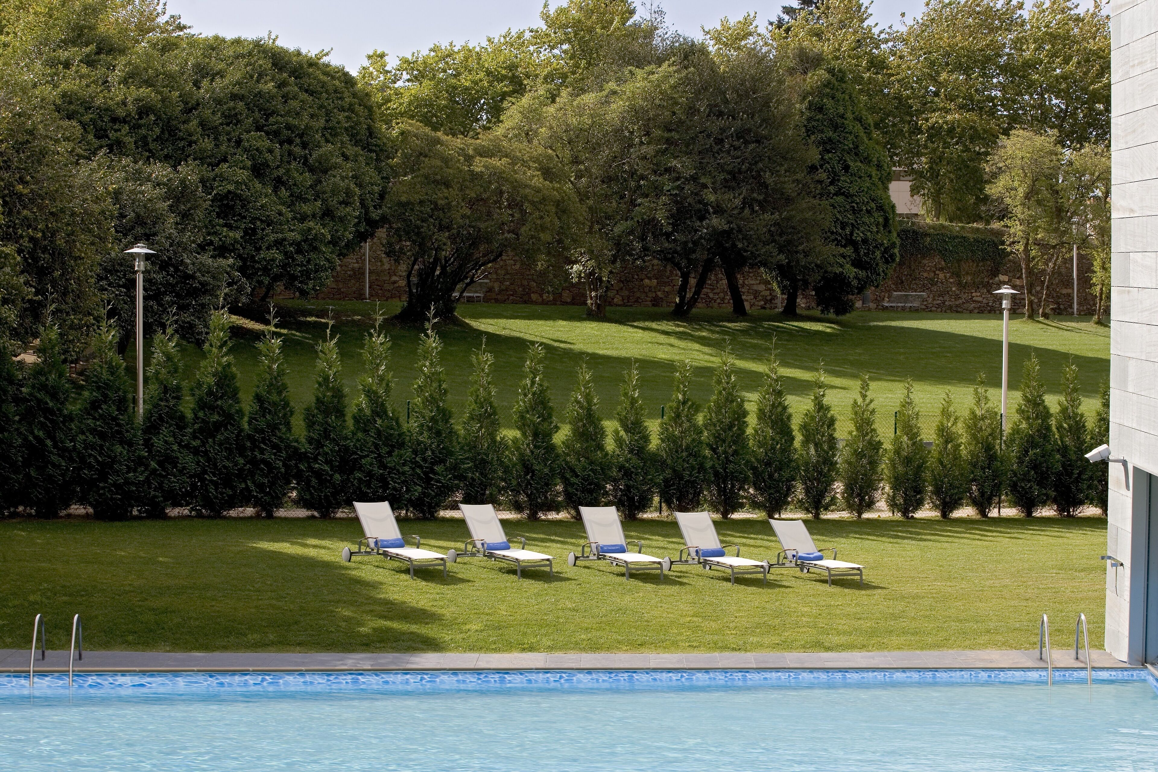 Un espace piscine avec des chaises longues et un mur de pierre en arrière-plan.