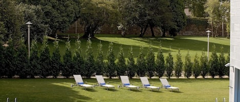 A pool area with lounge chairs and a stone wall in the background.
