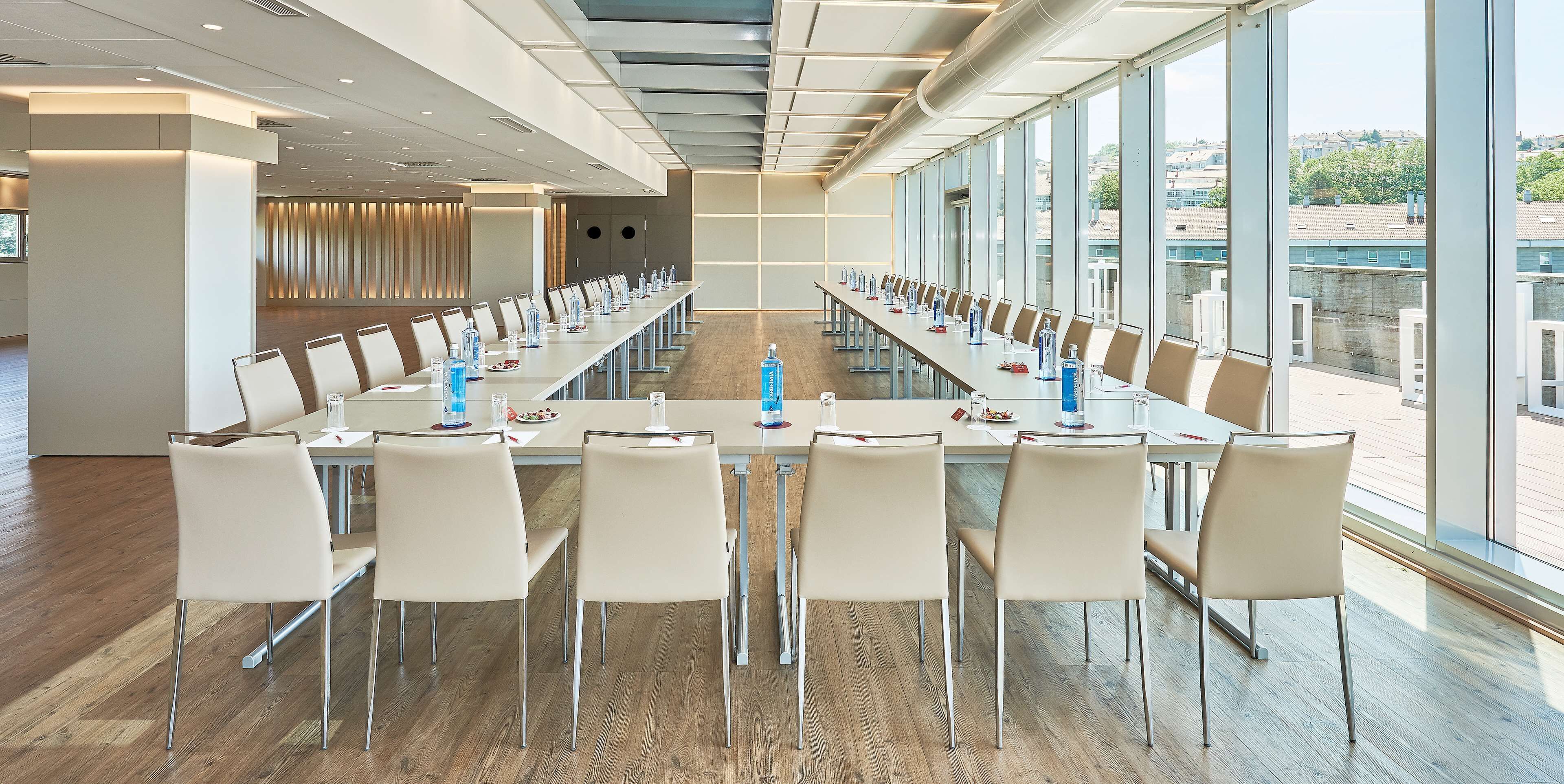 A long conference table with chairs, water bottles, and plates of food.