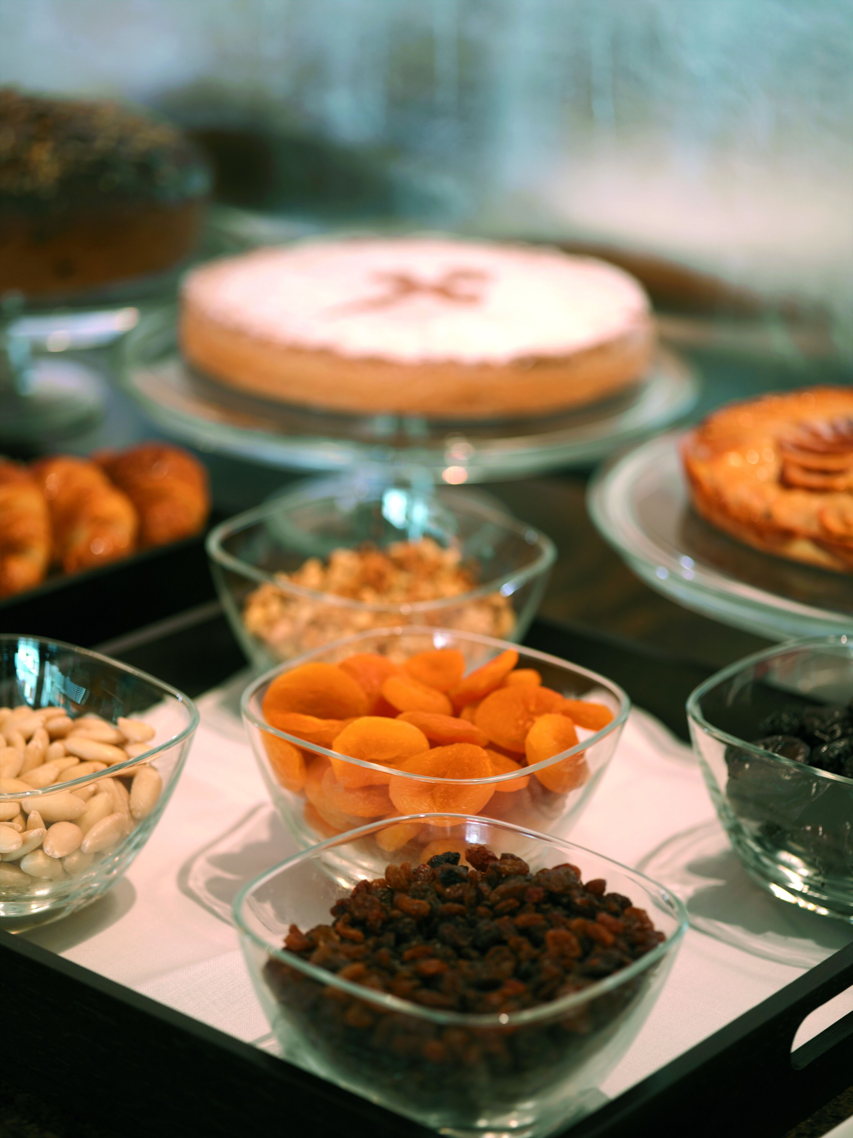 A buffet table with various food items including a cake, pastries, and bowls of nuts and dried fruits.