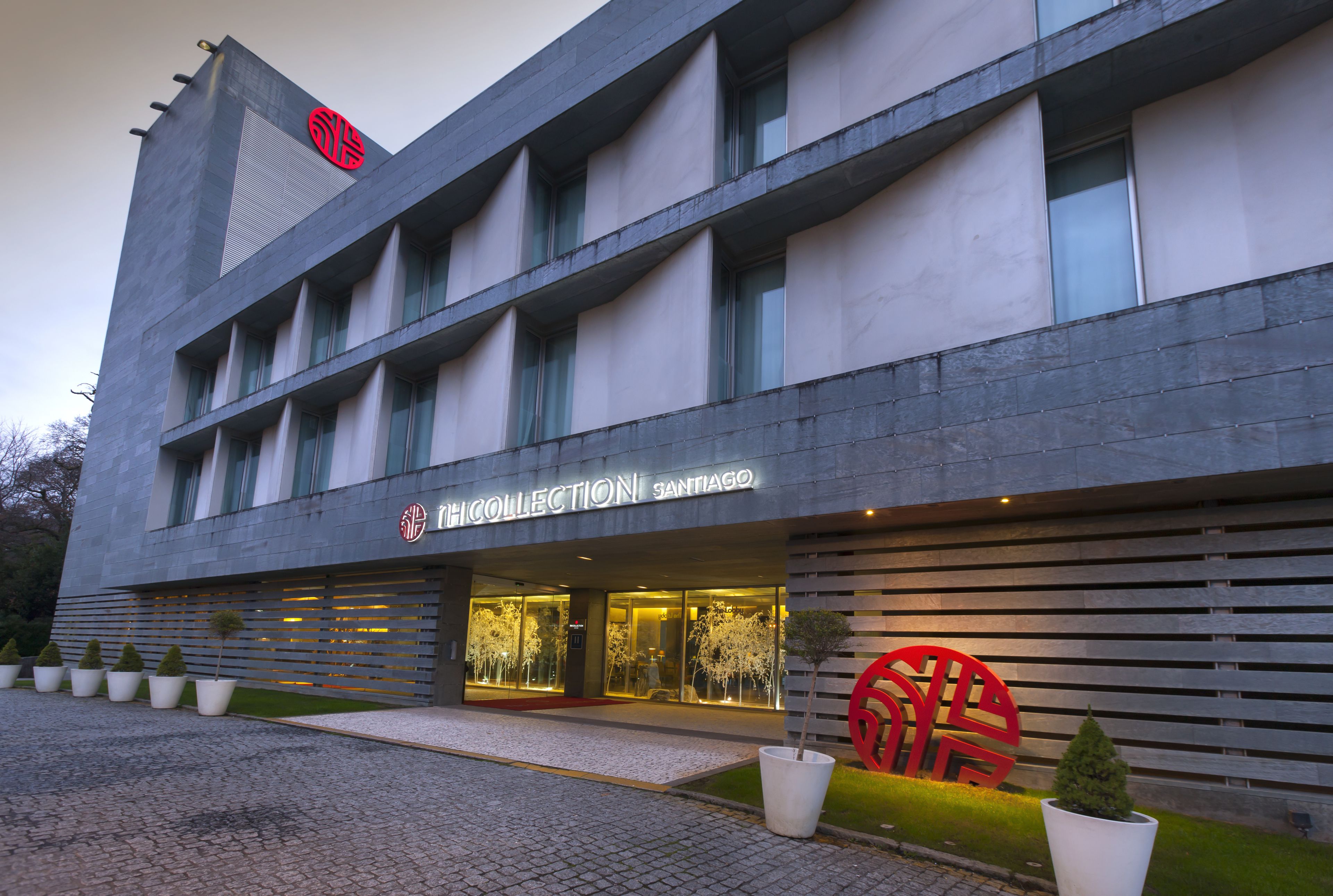 A modern building with a large glass entrance, a prominent logo, and a name sign.